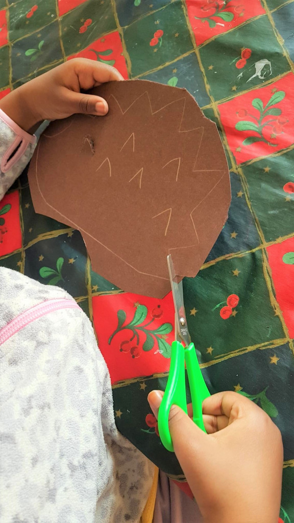 Lapsi leikkaa kartongista siilin muotoa irti.