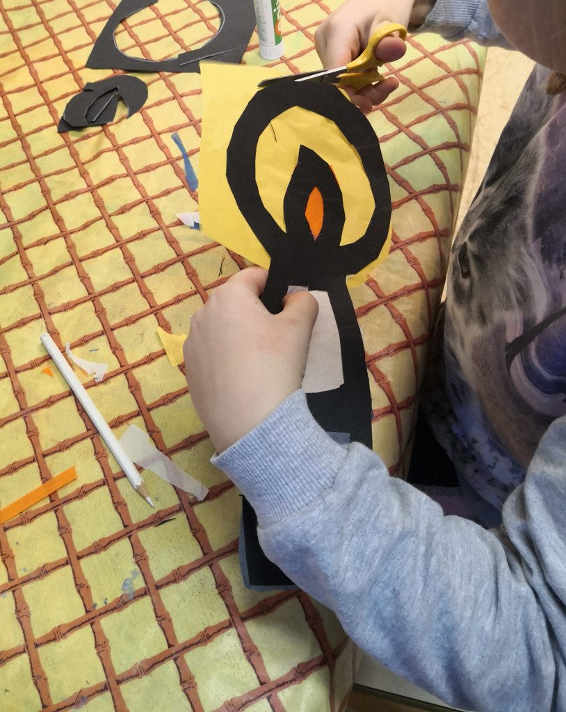 Lapsi leikkaa silkkipaperia kynttiläaskartelunsa ympäriltä.
