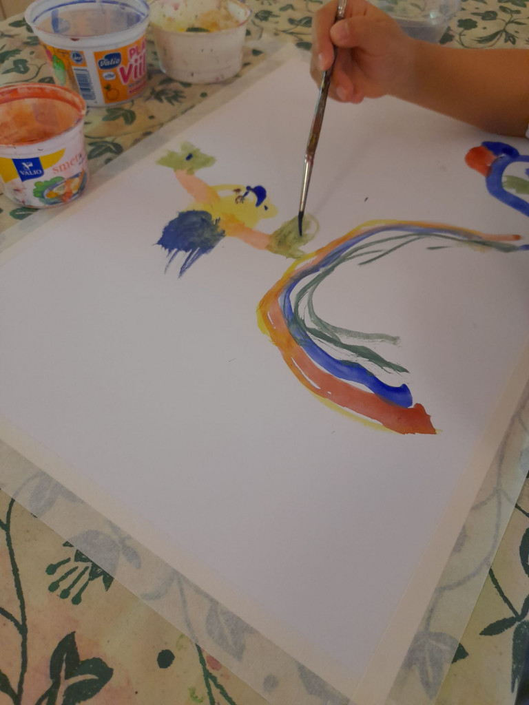 Lapsi maalaa vesiväreillä sateenkaaren. 
