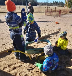 Lapset leikkivät hiekkalaatikolla. 