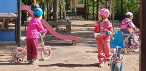 Tytöt ajoivat pyörällä päiväkodin pihalla.