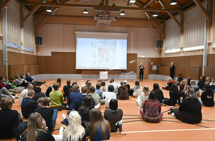 studerande samlade i en gymnastiksal och lyssnar på ett föredrag