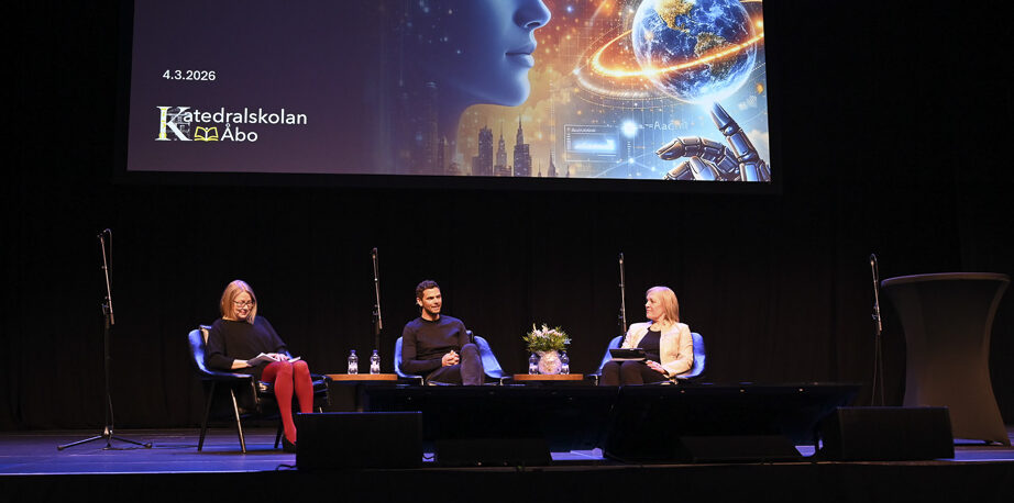 Tre personer sitter på en scen och diskuterar