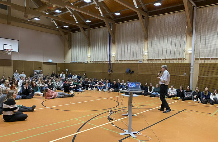 studerande lyssnar på föreläsare i en gymnastiksal
