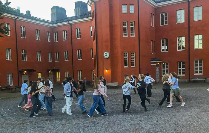 Ungdomar dansar utanför skolbyggnaden