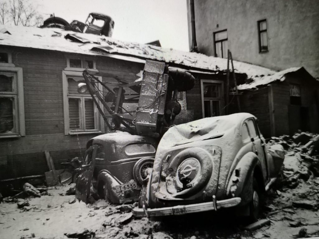 Mustavalkoinen museokuva Porista talvisodan ajalta. Kuvassa näkyy taustalla talo ja edessä kaksi romuttunutta autoa.
