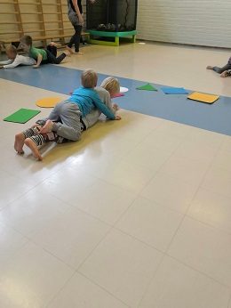 Jumppasalissa neljän lapsen pitää liikkua pareittain niin että toisen vatsa on kiinni lattiassa ja toisen vatsa parinsa selässä.