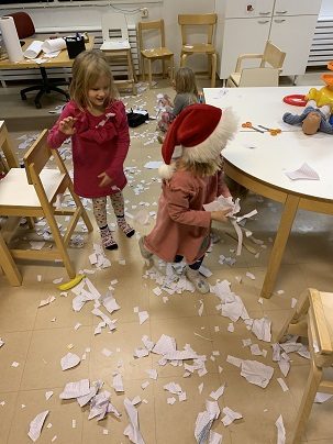 Kaksi lasta valmistautuu lumen eli paperisilpun heittämiseen
