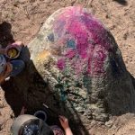 Lapset maalaavat vesiväreillä isoa kiveä.