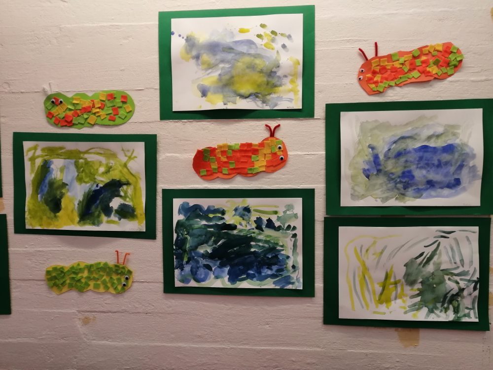 lasten vesivärimaalauksia ja toukka-askarteluja seinällä