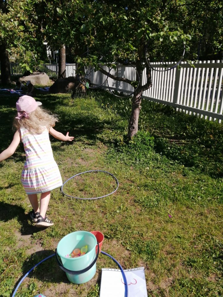 lapsi heittää vesi-ilmapalloa renkaan läpi tarkkuusheittona