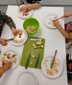 lapset leikkaavat omenalohkoja lautasille pöydän ääressä