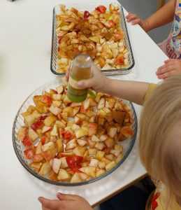 lapset sirottelevat kanelia omenoiden päälle