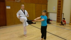 Jonatanilla on jännät paikat, kun mustavöinen taekwondo-ohjaaja Roosa Närhi näyttää potkun mallia.