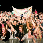 Kuva ihmisjoukosta konserttilavan edessä kannustamassa banderollin kanssa.