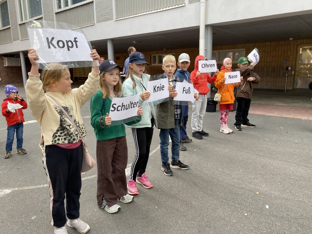 Oppilaita ulkona pitämässä kylttejä, joissa on saksankileisiä sanoja