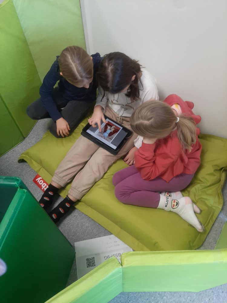 Kolme kolmasluokkalaista oppilasta pelaamassa yhteisellä iPadilla Kielikarnevaali-peliä.