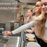 Ruokalinjastolla oppilaita jotka kädet ojentuneina joko ottavat puhdasta vettä juoma-automaatista tai juovat vettä lasista.