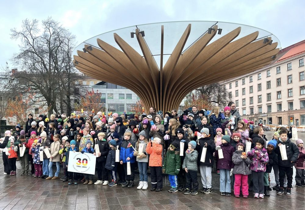 Suuri joukko lapsia seisoo ryhmänä Turun kauppatorilla laulamassa.
