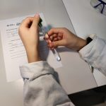 Lähikuvassa oppilaan kädet pitelevät koeputkea.