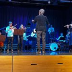 Lavalla soittaa orkesteri. Etualalla on selin kapellimestari.