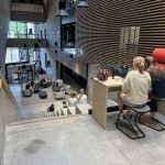 Oppilita syömässä korkeassa Aurumin sisätilassa, joka laskeutuu auditoriomaisesti avoimesti korkealta etualalta alas kohti ulko-ovea.