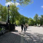 Oppilaita kävelemässä vehreässä puistossa mukulakivikadulla. Taivas on sininen.
