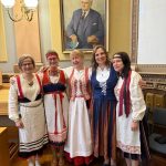 Viisi opettajaa rinnakkain iloisesti esittelemässä kansallispukujaan.