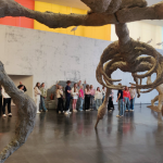Oppilaita ison kuvitteelisen modernin dinosaurusluurangon äärellä ja alla.